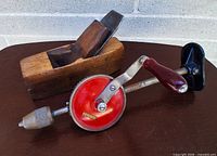 Auburn wooden hand plane beside Meister eggbeater drill showing overall lot