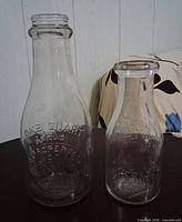 Front view of both embossed glass bottles showing size difference and lettering