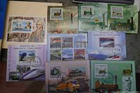 Group of souvenir stamp sheets showing transportation themes such as early locomotives and trains