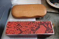 Two hard eyeglass cases: tan textured shell and red faux-snakeskin rectangular box