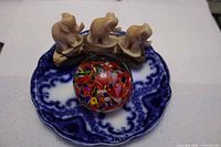 Top view showing all three items together: carved elephants, plate beneath, paperweight centred