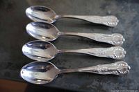Four matching silver-tone spoons front view