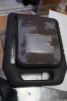 Black fabric zippered pouch with flap holding multi-tool kit