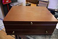 Closed dark wood flatware chest with brass knobs