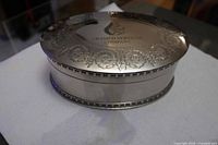 Three-quarter view of jewelry casket showing lid, sides, and logo