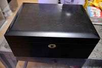 Front view of black wooden cigar humidor with brass keyhole