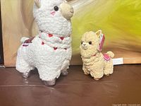 Both alpaca plush standing side by side for scale and condition