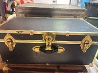 Front view of black footlocker with brass hardware