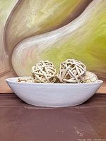 Side view of white bowl with rattan spheres inside