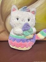 Front view of FAO Schwarz Glow Kittycorn plush showing pastel horn, cupcake, scalloped body