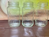 Front view of three clear Atlas Mason jars showing embossed lettering