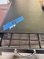 Top view of black metal drawer with mesh interior visible