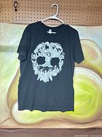 Front of black T-shirt with white skull design displayed on hanger