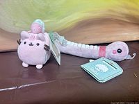 Pusheen Squisheen cat plush and Bellzi Nakormi worm plush side by side