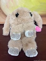 Front view showing plush tan rabbit shape and rhinestone paw pads