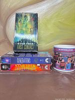 Three VHS tapes and ceramic mug on table