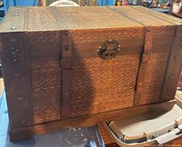 Front view of Victorian flat-top trunk showing woven panels, metal straps and clasp