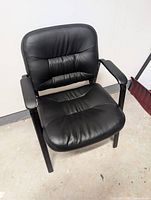 Front angled view of black faux leather office chair showing seat, back and arms