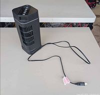 Front angled view of black desktop tower fan with cord visible