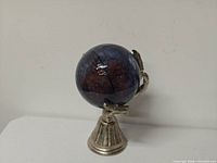 Front view of glass orb on skeletal hand stand