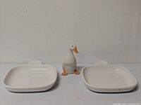 full set showing duck figurine centered between two handled dishes