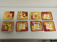 Eight square plates displayed in two rows on table