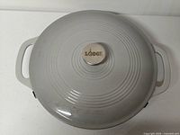 Top view of closed braiser showing light gray lid, concentric ridges, Lodge knob