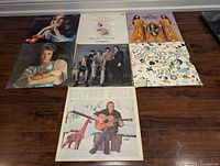 Seven LP record sleeves laid out on floor showing all titles