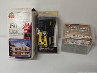 Three retail-packaged items: Yule Rite lights box, Stanley MiniTripod flashlight package, Paulin screws box