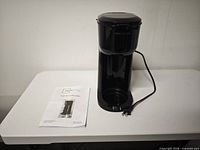 Front view of coffee maker and manual