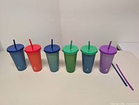 Front view of six tumblers lined up left to right with two spare straws on side