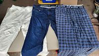 White sweatpants, blue denim jeans, blue plaid boxer shorts displayed side by side