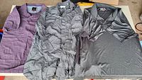 All three shirts laid flat: purple polo, grey patterned button-up, charcoal polo