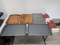 All five baking sheets, cutting board, pair of mitts laid out on table