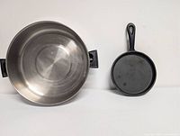 Stainless steel saucepan beside small cast iron skillet, overhead view