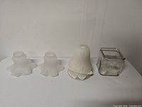 entire lot showing two small ruffled shades, stack of bell shades, clear glass jar