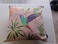 Front view of pink cushion with hummingbird and foliage print