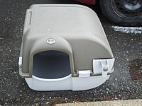 Front view showing entry opening, tan top, white base, latch closures