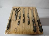 Full view of sealed board holding five knives, honing rod and shears
