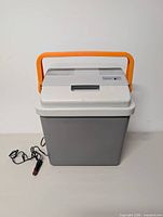 Front view of gray portable cooler/warmer with orange handle and 12 V cord