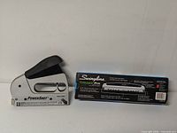 PowerShot staple gun and boxed Swingline hole punch side by side