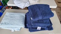 Stacked navy towels and folded aqua towel on table