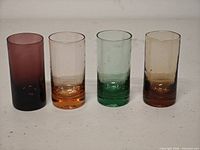Front view of four colored hand-blown shot glasses