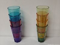 Two stacks of eight multicolor acrylic tumblers showing color variety and faceted design
