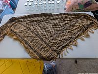 Full view of tan and black keffiyeh scarf laid flat on table