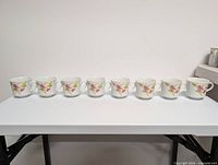 Eight matching floral porcelain cups lined on table