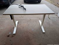 Desk front view with crank handle visible on right and power strip cord on top