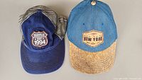 Two hats side by side showing front logos and brim materials