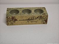 Front view of wood block showing three metal cups and end of Einstein quote