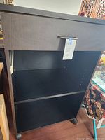 Front view of cabinet showing drawer, open shelf, casters